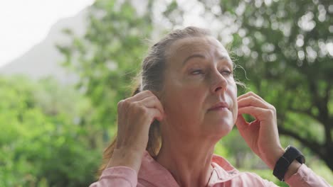 Senior-woman-using-wireless-earphones-in-the-park