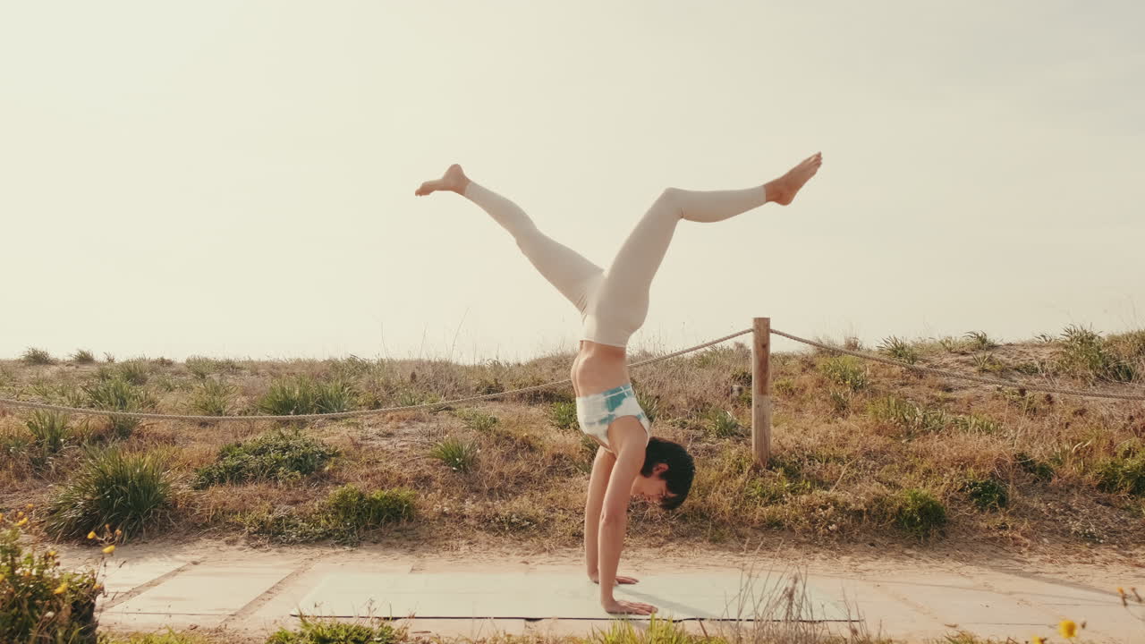 Frau in Handstand-Yoga-Pose im Freien auf einer Matte
