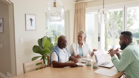 african american financial advisor and senior couple talking at home, slow motion