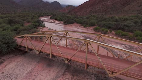 Eine-Rostige-Brücke-über-Ein-Trockenes-Flussbett-In-Der-Route-68,-Quebrada-De-Las-Conchas,-Cafayate,-Salta,-Argentinien,-Luftaufnahme