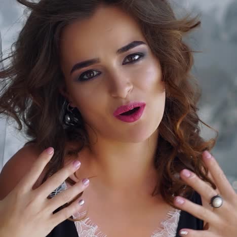 joyful girl with long brunette hair singing in modern white apartment.