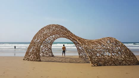 a unique beach structure creates a memorable interaction with nature and art amidst waves and sandy shores, capturing serenity and creativity by the ocean