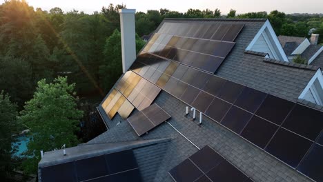 rooftop solar panels on house in american neighborhood. sunlight reflection on unit. green renewable clean energy theme. peaceful sunset scene in suburbia. drone close up shot
