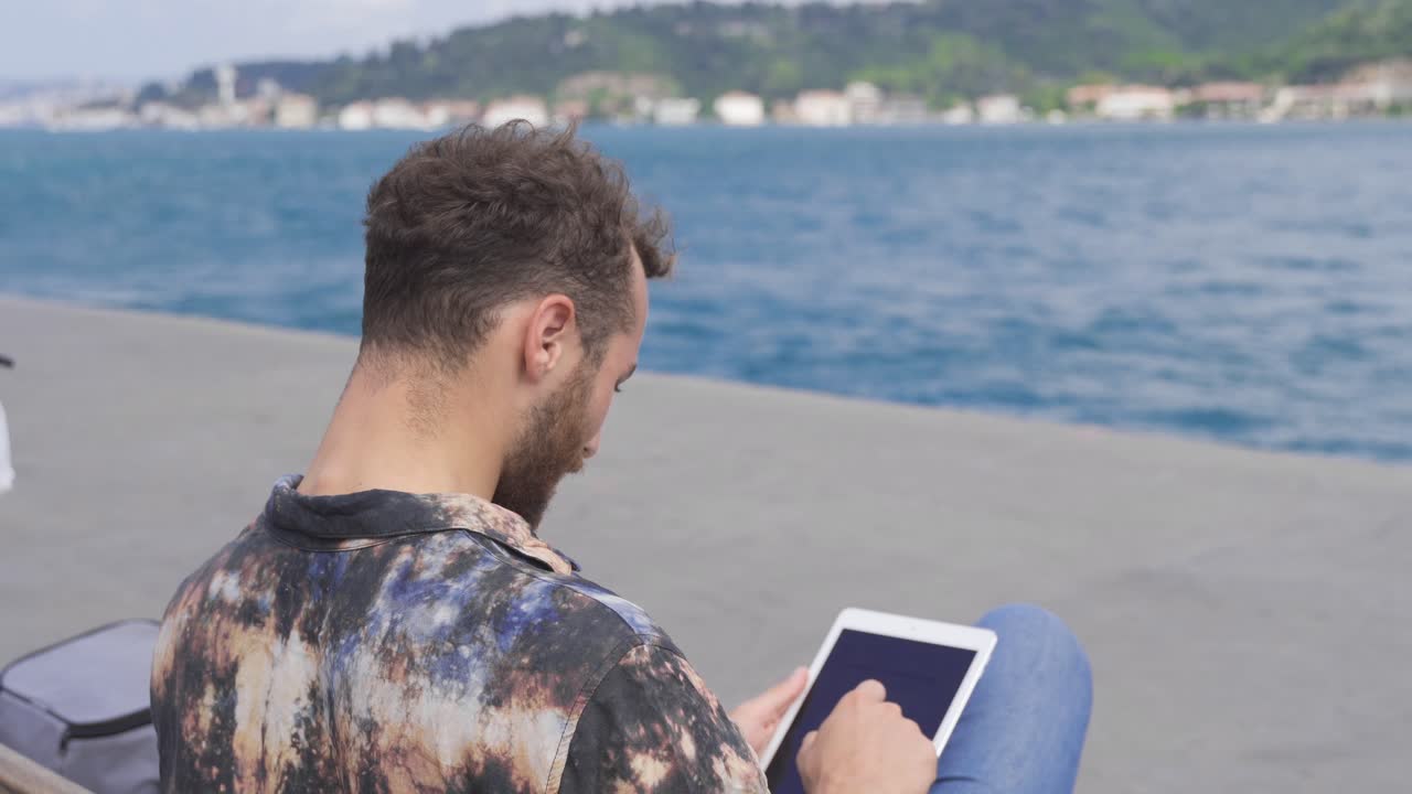 el hombre que trabaja en freelance trabaja en su tableta junto al mar.