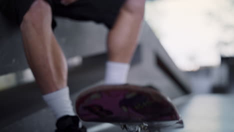 Unrecognizable-man-resting-with-pink-skate-board-at-urban-skate-park.