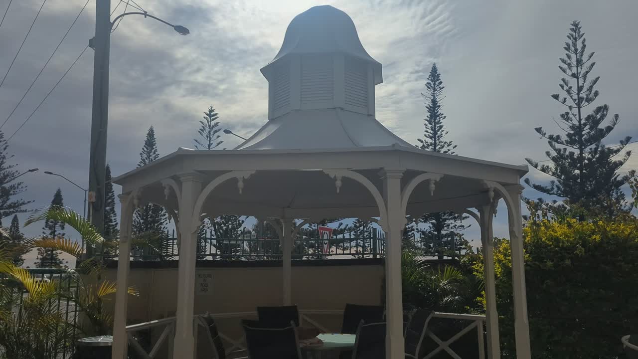 Pan up, Spa bath bubbling with poolside arbour and early morning sky in background.