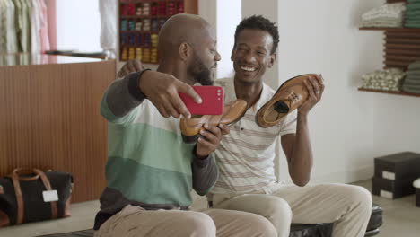 happy black male couple taking selfie holding leather shoes.