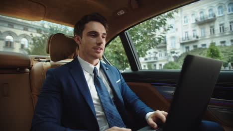 business man having video chat on laptop in car