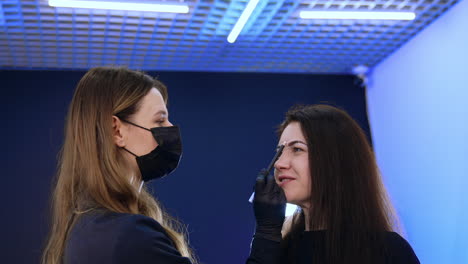 Cosmetologist drawing marks on the woman's face. Client is prepared for the permanent eyebrow make up.
