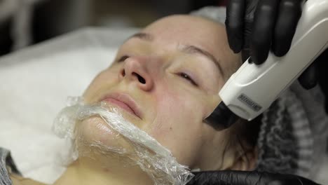 cosmetologist make ultrasonic face cleaning on woman face in beauty clinic salon