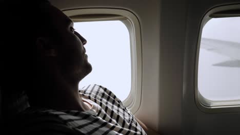 pasajero viajero mirando por la ventana en el avión, viajar en vuelo, hombre turista sentado en el avión