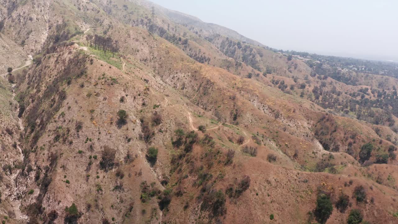 Aerial rising and panning shot of powerlines on the mountainside above Eaton Canyon, the origin of the wildfire in Altadena, California. 4K