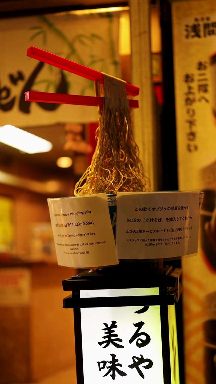 Espositore meccanico di noodle soba con bacchette in movimento fuori da un ristorante tradizionale di notte a Tokyo