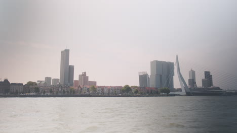 erasmusbrug aka the swan during the day with skyscrapers and cityscape in rotterdam, netherlands, wide shot