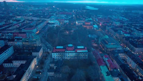 aerial drone backward moving shot over residential buildings surrounding a park in stockholm, sweden in evening time blue hour