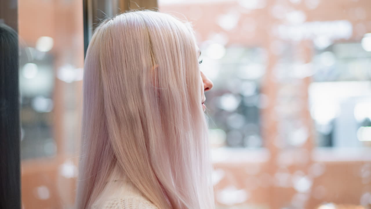serene observer looking through transparent elevator glass into mall interior with blurred shoppers reflection, pastel hair framing profile, soft light and bokeh creating calm contemplative mood