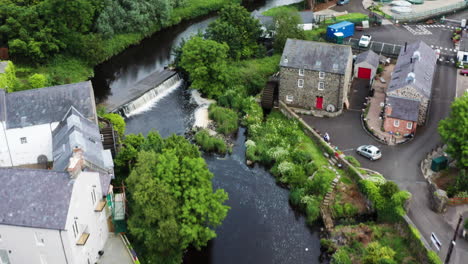 aerial shot of bushmills village in northern ireland with cars passing over stone bridge on bush river