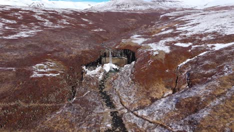 earthy volcanic landscape in frozen, iced winter waterfalls svartifoss basalt column, icelandic, nordic natural environment, travel destination