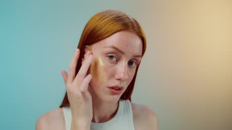 woman applying gold facial treatment