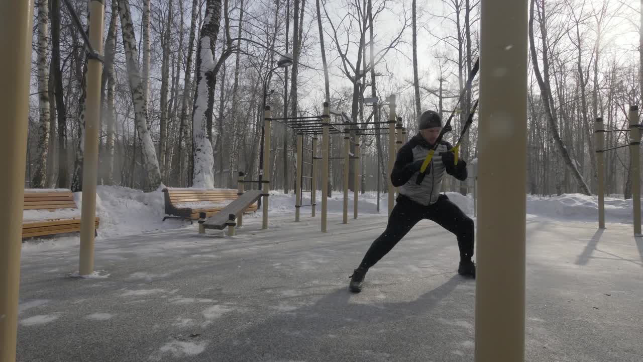 야외 스포츠 경기장에서 훈련하기 위해 trx 루프 장비를 사용하는 피트니스 남자