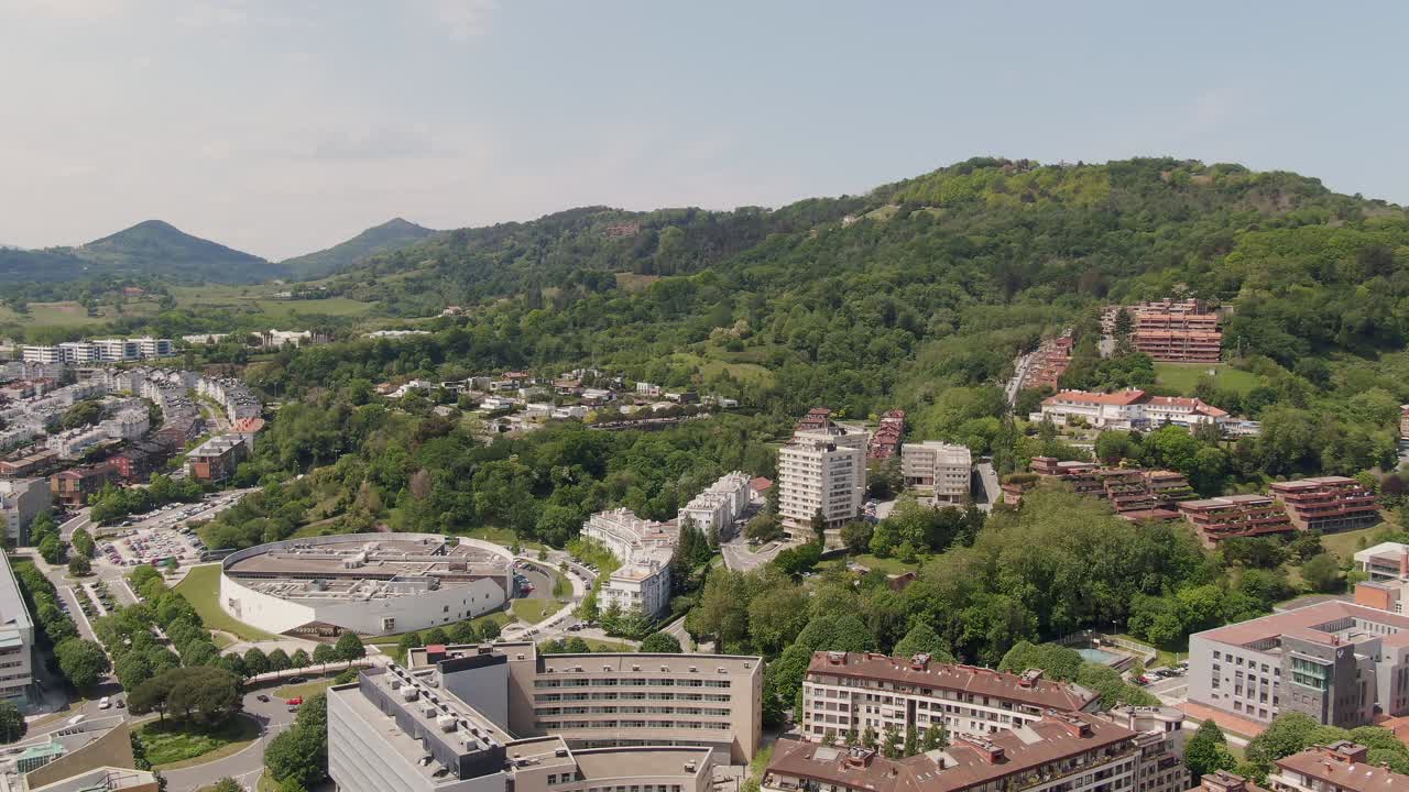 distrito residencial con edificios de apartamentos y colinas forestales de san sebastián, vista aérea de drones