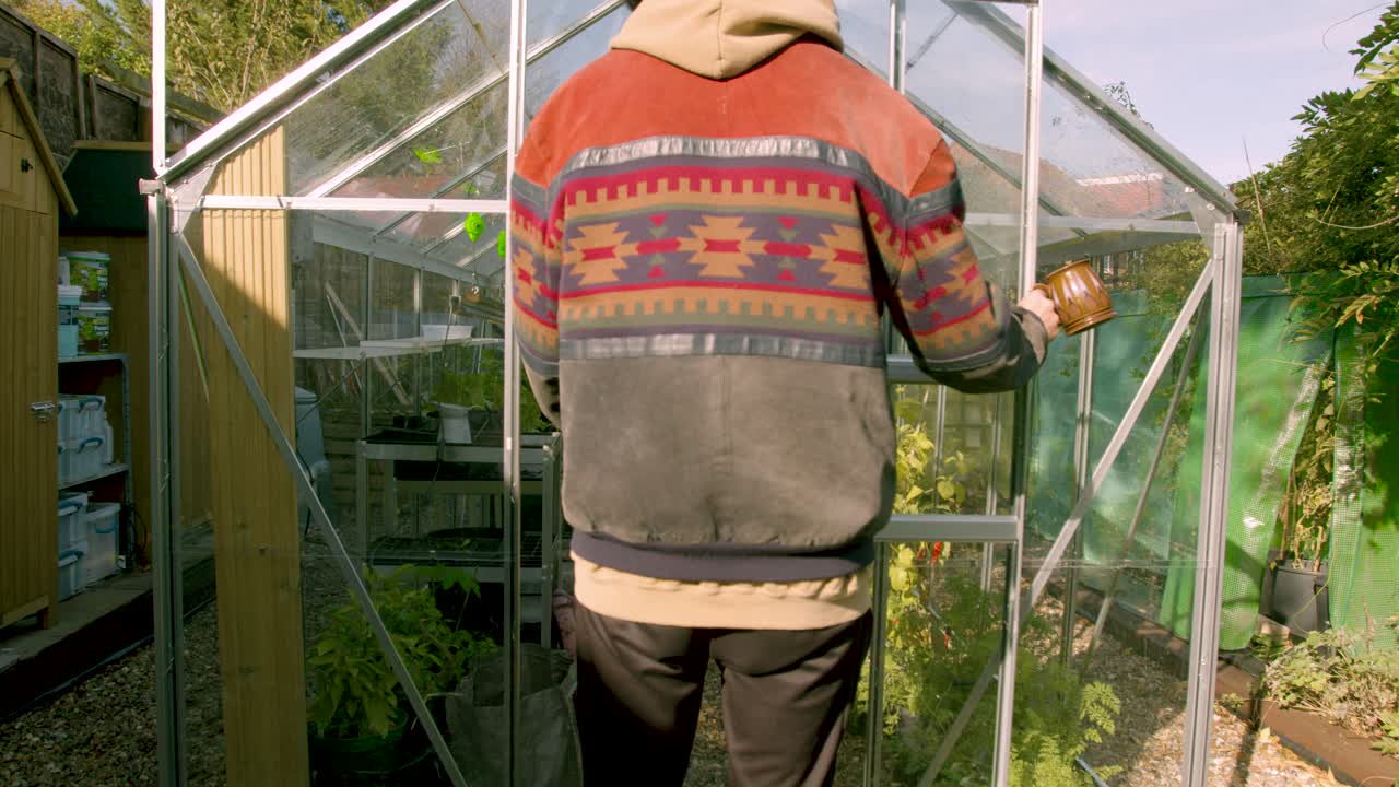 el hombre hipster abre la puerta de la casa verde y entra para revisar las plantas