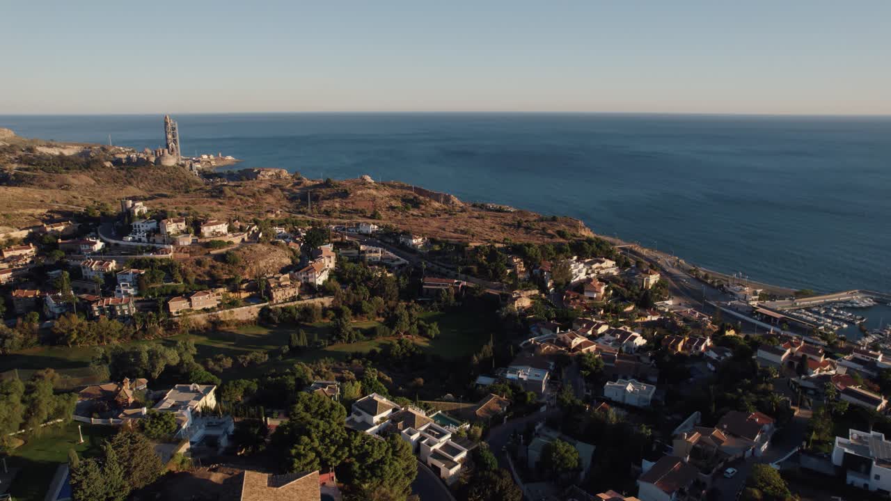 área residencial de sobrevuelo aéreo ubicada en una colina en malaga y playa candado con océano azul al atardecer