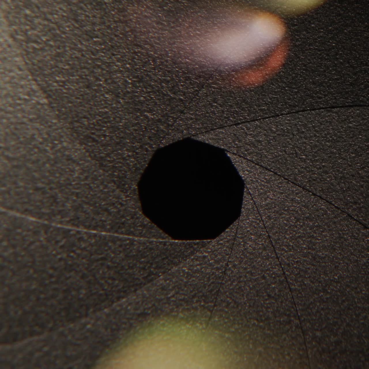 primer plano de la apertura de la lente iluminada por un haz de luz con deslumbramiento