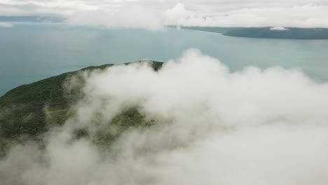 drone aerial panning around tropical forest island above the clouds