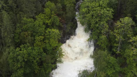 Drone-shot-of-powerful-Eas-Chia-aig-waterfall-in-flood-with-green-forest-surrounding