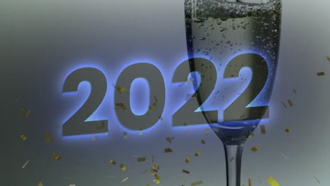 Animation-of-2022-text-over-confetti-and-glass-of-champagne