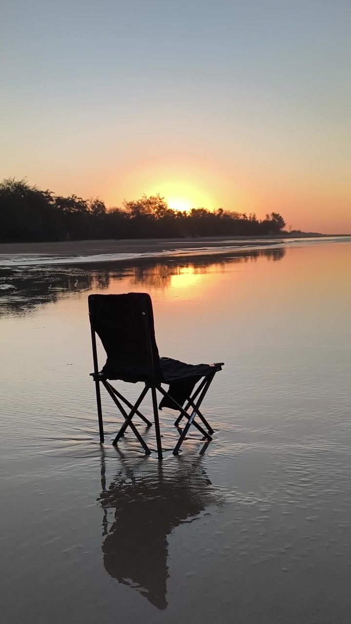 Sedia pieghevole vuota sulla spiaggia al tramonto