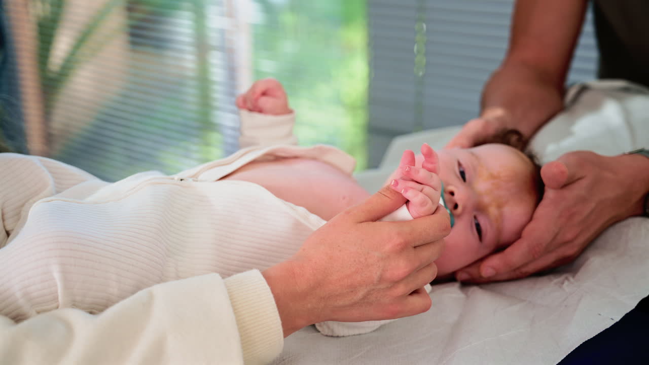 Close up of a baby grasping an adult's fingers during a medical moment