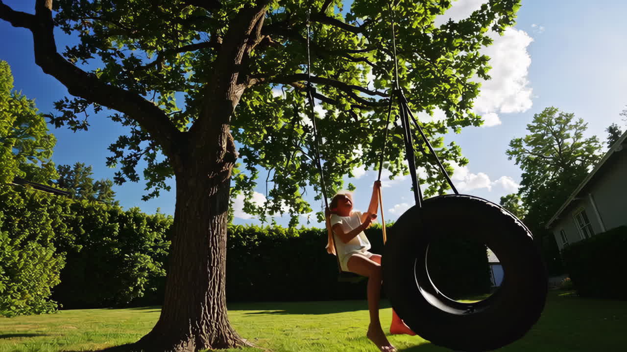 Young girl playing on a tire swing in a sunny backyard