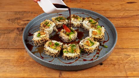 Close-up-of-plate-of-sushi-being-doused-in-eel-sauce