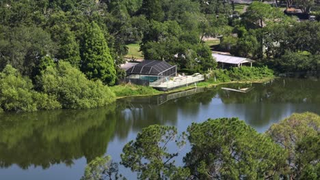 indoor pool with glassed roof in luxury neighborhood and private river access. aerial view. sunny day with green trees in summer. wide shot. brandon, florida.