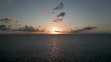 sunset on horizon aerial drone shot center frame with clouds and calm caribbean ocean water