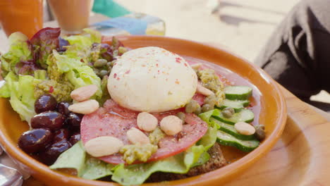 A-café-served-salad-featuring-lettuce,-mozzarella,-and-nuts-on-a-plate,-offering-a-nutritious-and-tasty-meal-option