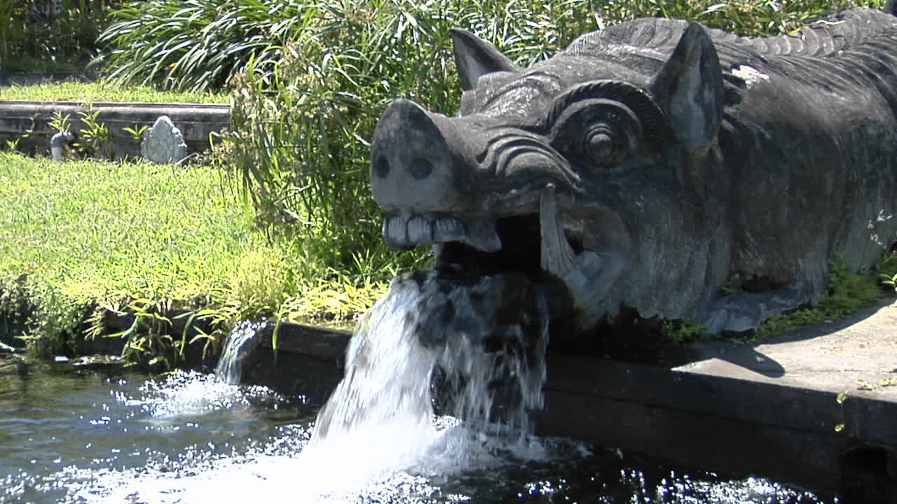 발리의 물 사원에 있는 멧돼지 동상의 입에서 물이 쏟아집니다.