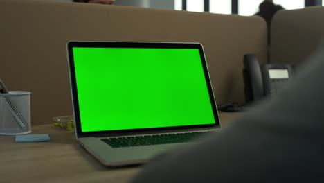 hombre de negocios usando una computadora portátil de pantalla verde en la oficina. computadora de pantalla verde