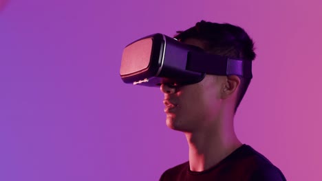 Fröhlicher-Asiatischer-Mann-Mit-VR-Headset-Auf-Violettem-Hintergrund,-Kopierraum,-Zeitlupe