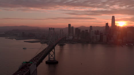 aerial shot along bay bridge towards downtown san francisco at sunset