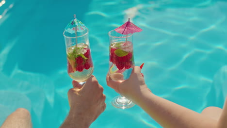 una pareja disfrutando de cócteles junto a la piscina.