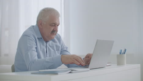 Ein-Mann-Mittleren-Alters-Kommuniziert-Mithilfe-Der-E-Mail-Technologie-Auf-Einem-Laptop-Und-Tippt-Im-Internet-Von-Zu-Hause-Aus-Nachrichten