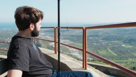 man sitting on overlook with scenic mountain view