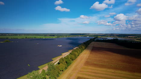 Toma-Aérea-Amplia-De-La-Granja-De-Paneles-Solares-Instalada-En-El-Campo-Agrícola-Durante-El-Día-Soleado-En-Verano