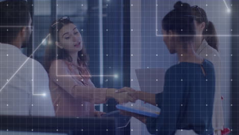 animation of grid processing data over two diverse businesswomen shaking hands at office meeting