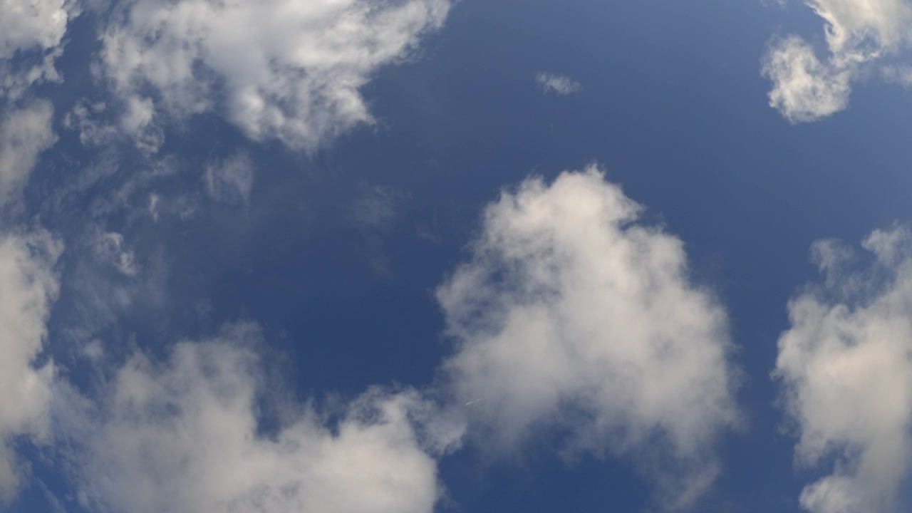 Weitwinkelansicht eines Flugzeugs, das durch einen blauen Himmel mit Wolken fliegt