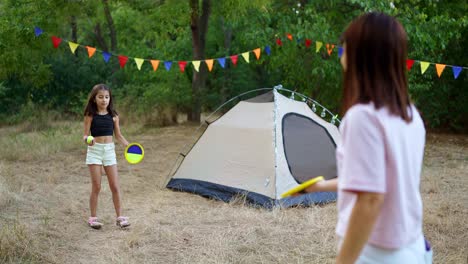 mother and daughter playing frisbee in a camping area