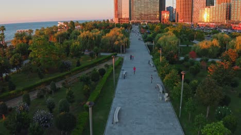 Flying-Above-City-Park-At-Sunset-Near-Black-Sea-Expanse